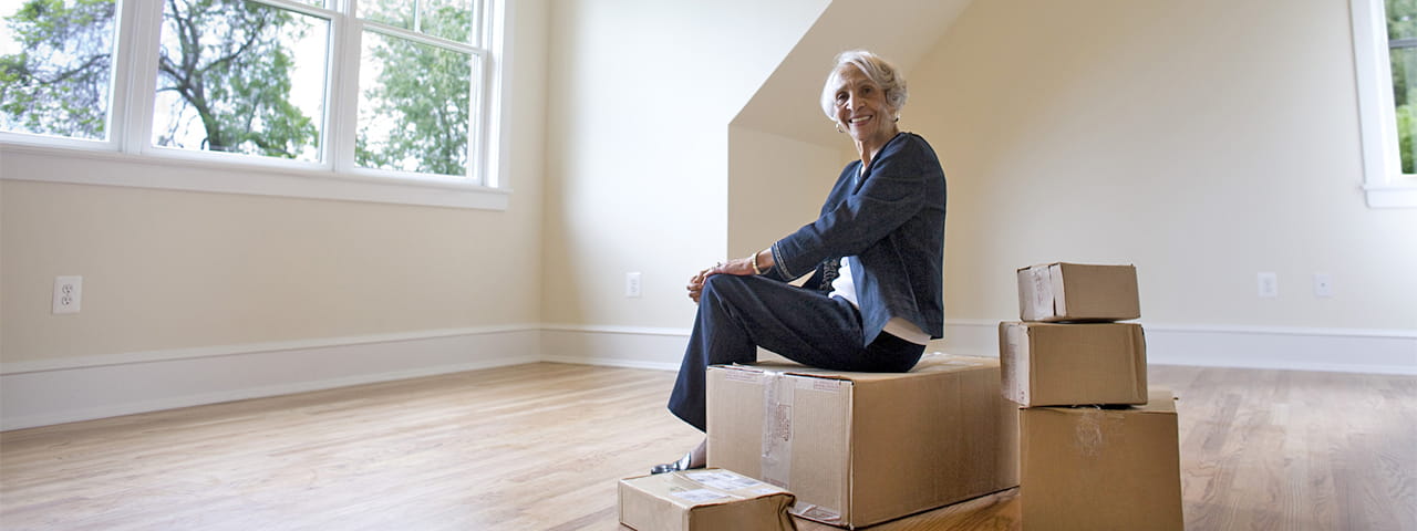 Vi at Lakeside Village resident sits on boxes in empty room