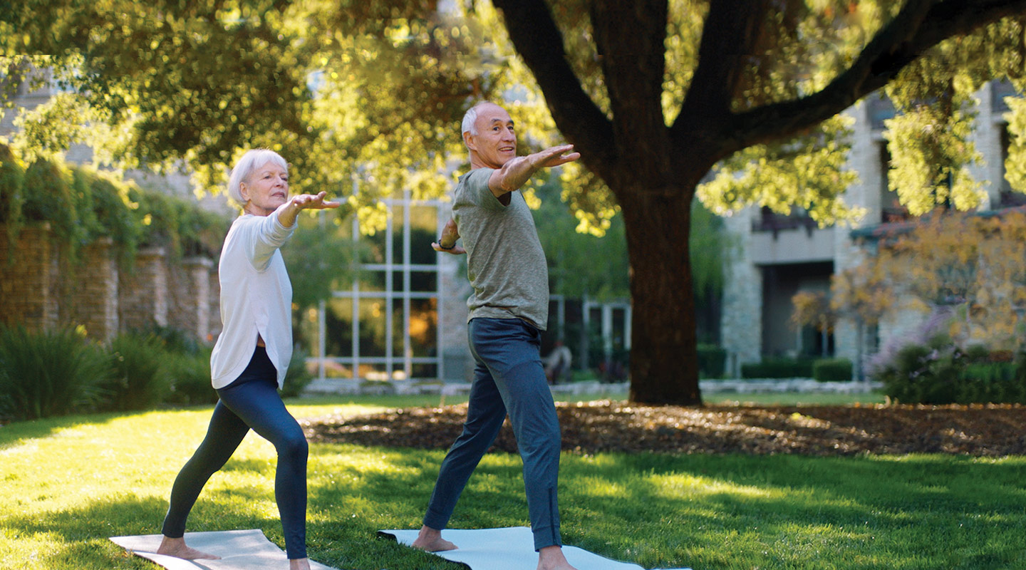 Two people do yoga outside a Vi community
