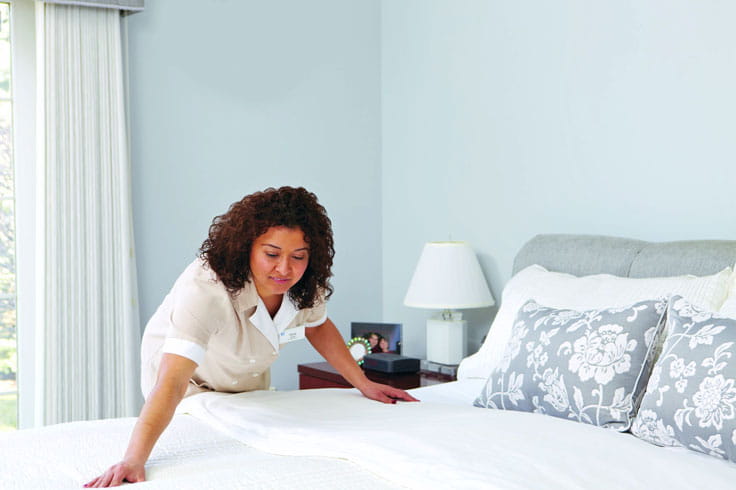 A housekeeping team member makes a bed.