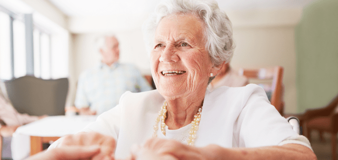 An older woman is holding hands with someone out of the frame.