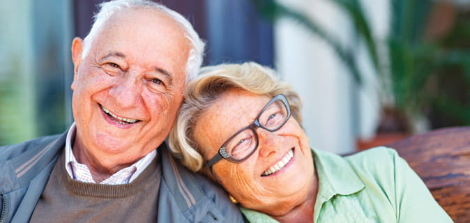 A woman puts her head on a man's shoulder. Both are smiling.