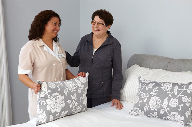 A nurse helping to make the bed.