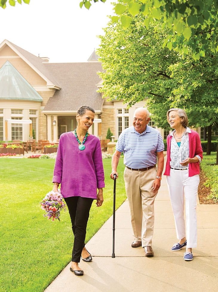 Two women and a man walk down the path at Vi at The Glen.