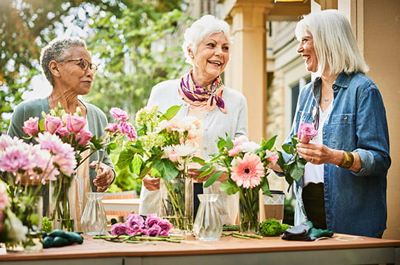 Three women outside with flowers.