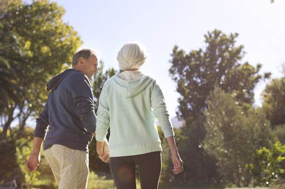 A man and woman walk away from the camera with their backs turned.