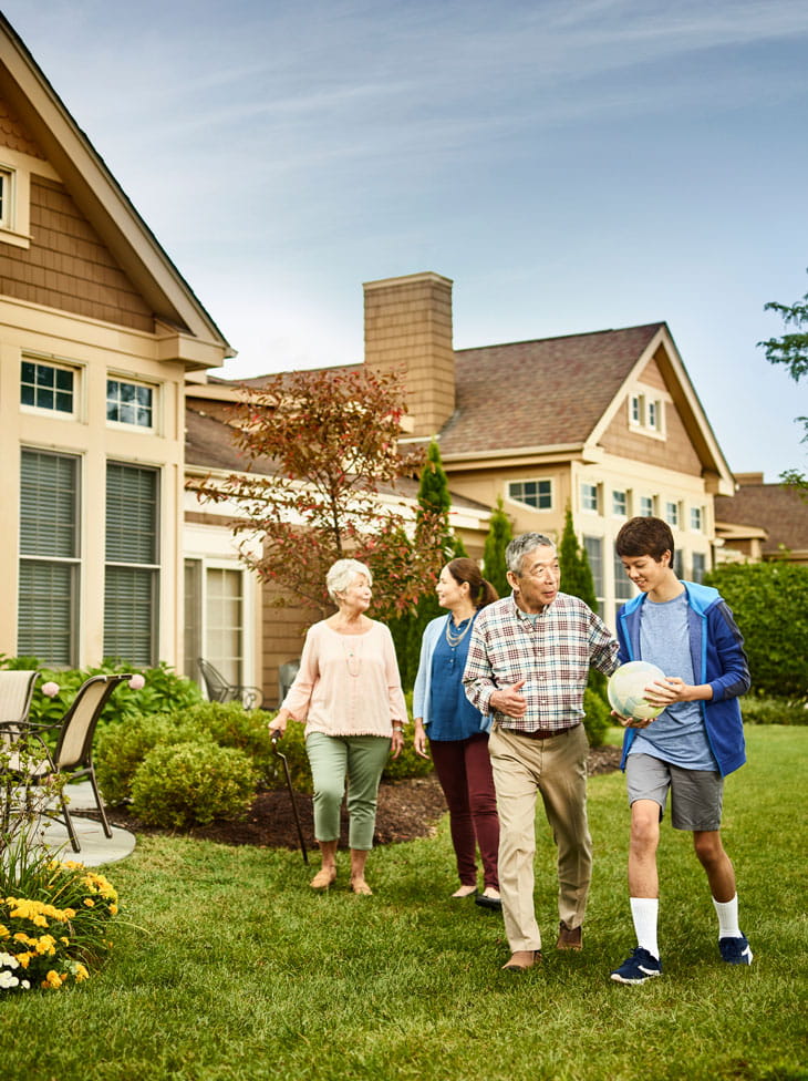 A multigenerational family walks across a lawn.