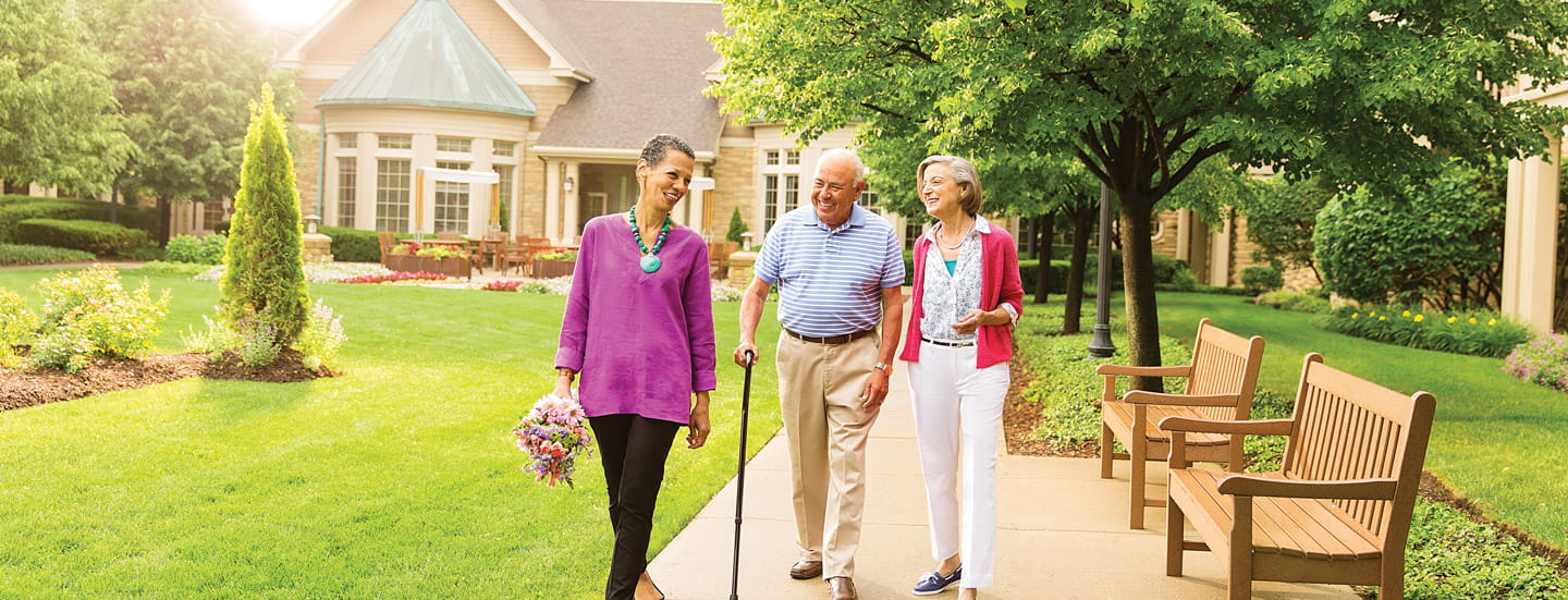 Two woman and a man walk down a path at Vi at The Glen.