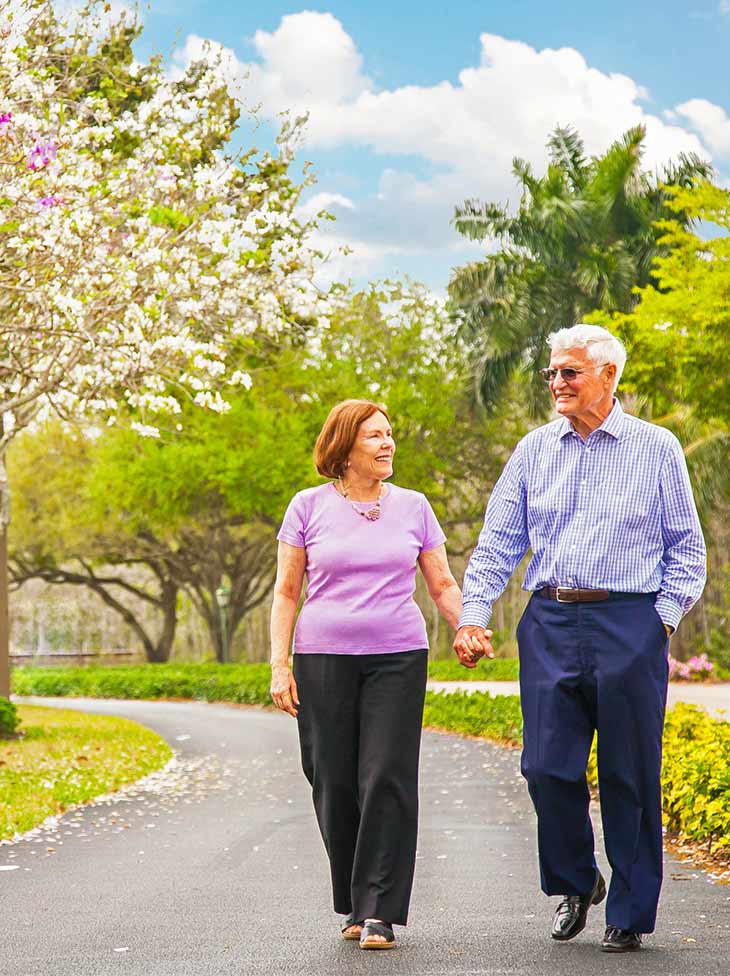 A couple holding hands walking outside. 