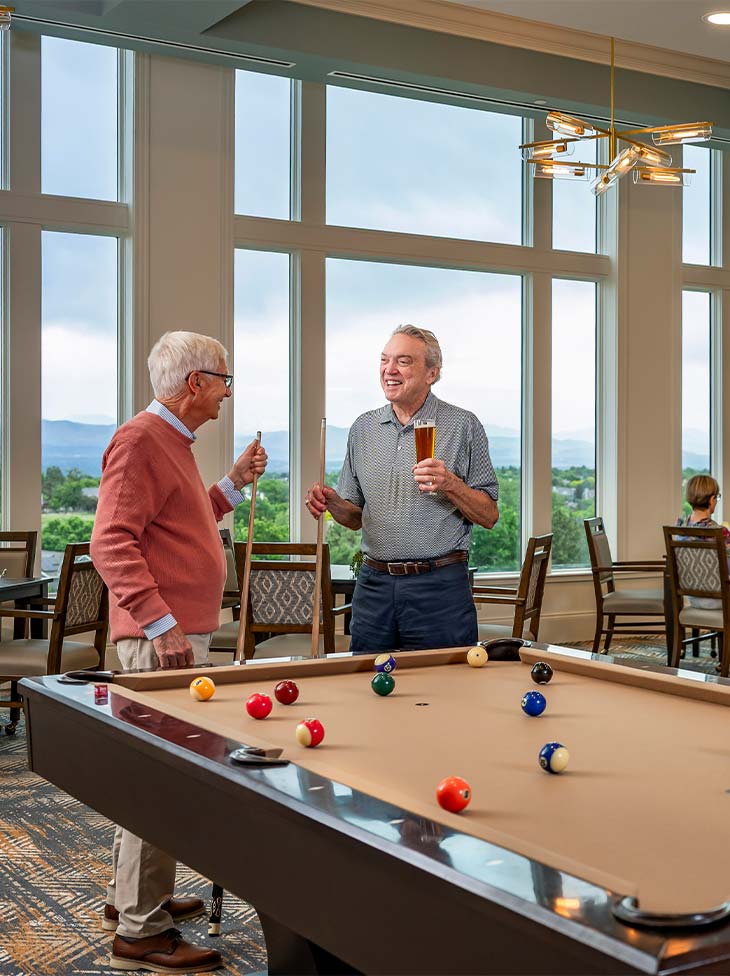 Two men drinking beer and playing pool. 