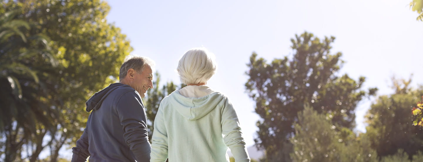 A man and woman hold hands while they walk.