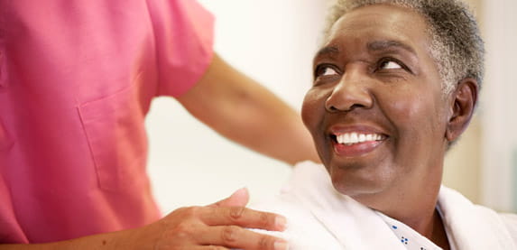 A woman in a robe looks back and smiles at a person in pink scrubs.