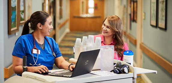 Two female nurses at their cart. 