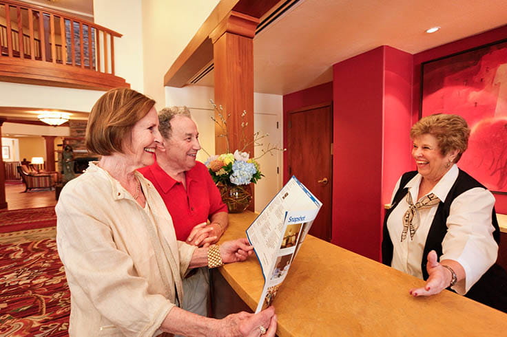 A couple stands by the concierge desk and talk to a staff member.
