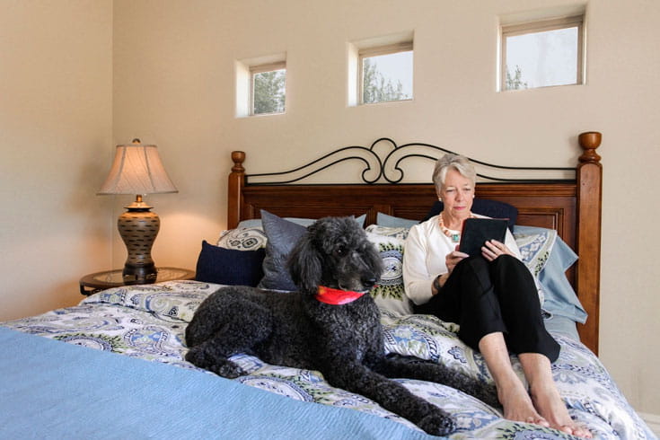 A woman reads with her dog in her Vi at Grayhawk home.