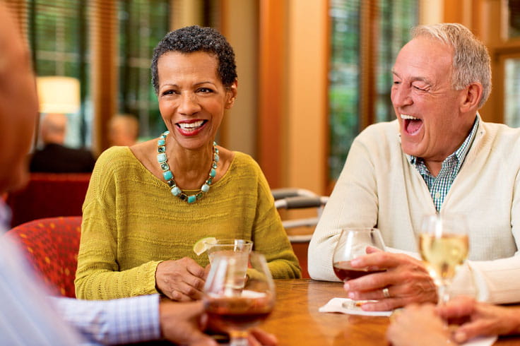 Men and women sit at a table together and laugh