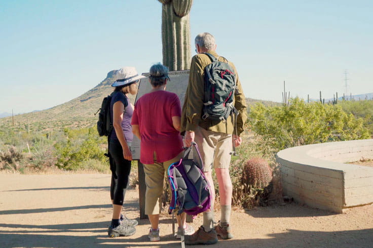 Hiking Club residents read a sign at a nearby park.