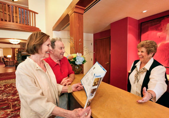 A concierge chats with staff at the front desk.