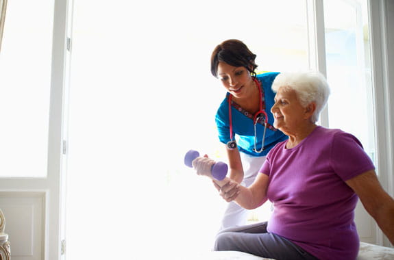 A woman lifts hand weights with a staff member.