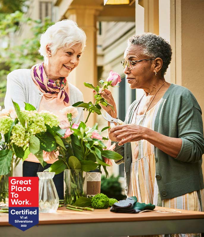 Women cut and arrange flowers together. 