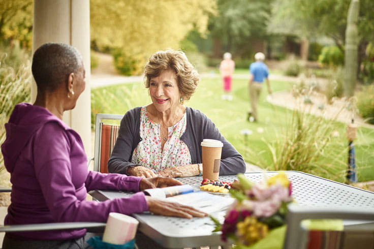 Two women sit outside and chat.