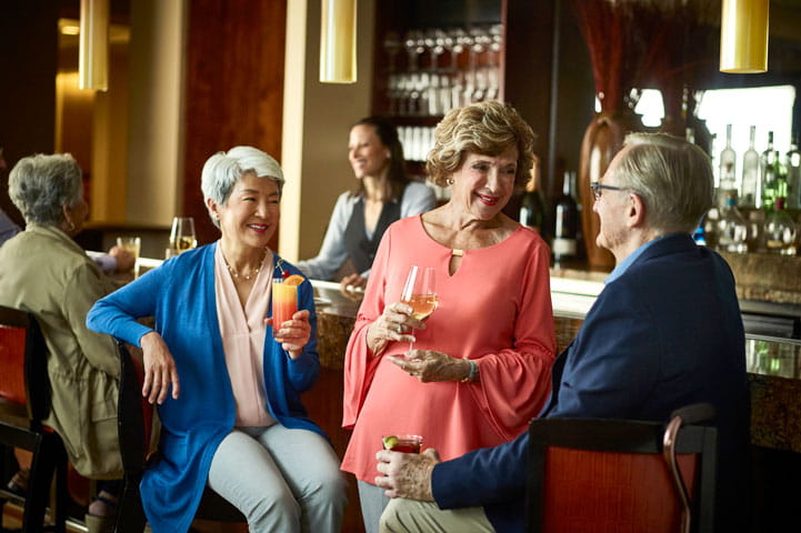 Three people chat together at a bar.