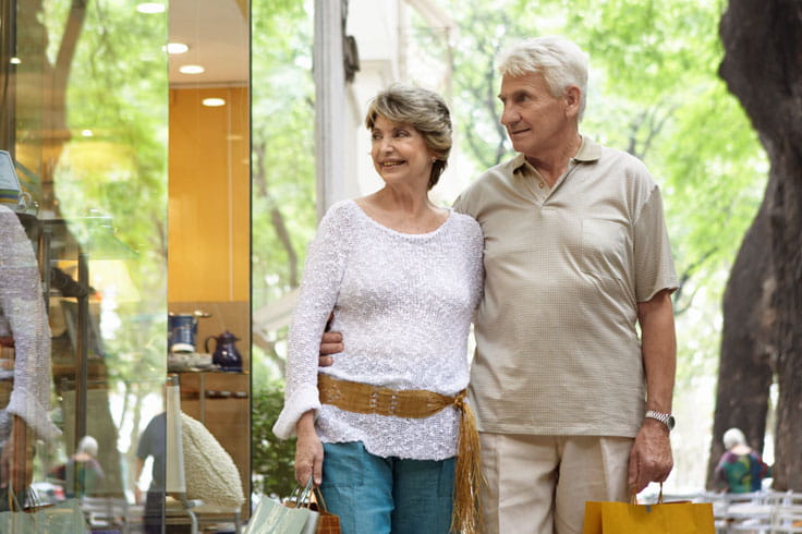 A couple walks down the street in a shopping district.