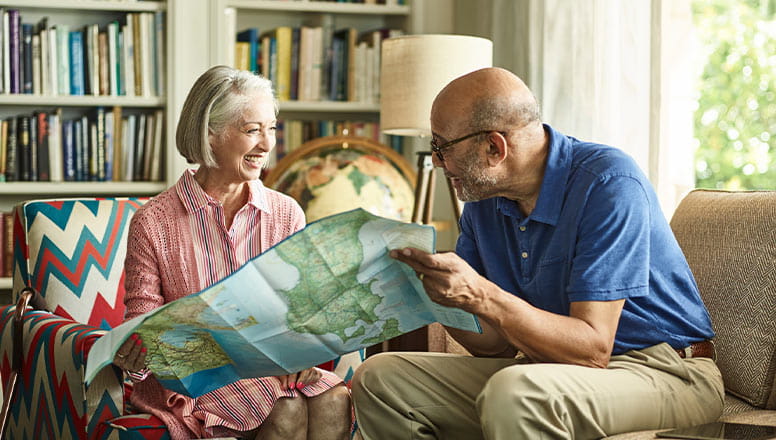 A man and a woman sitting and smiling looking at a map. 