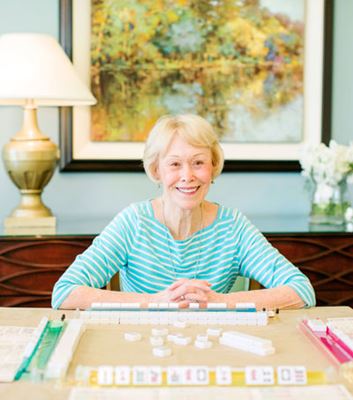 Nancy Dolan smiles while sitting at a table set for mahjong.