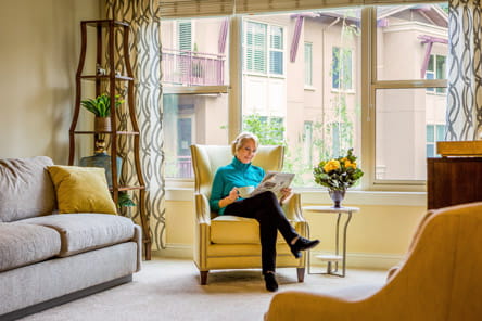A woman reads in her living room at Vi at Palo Alto.