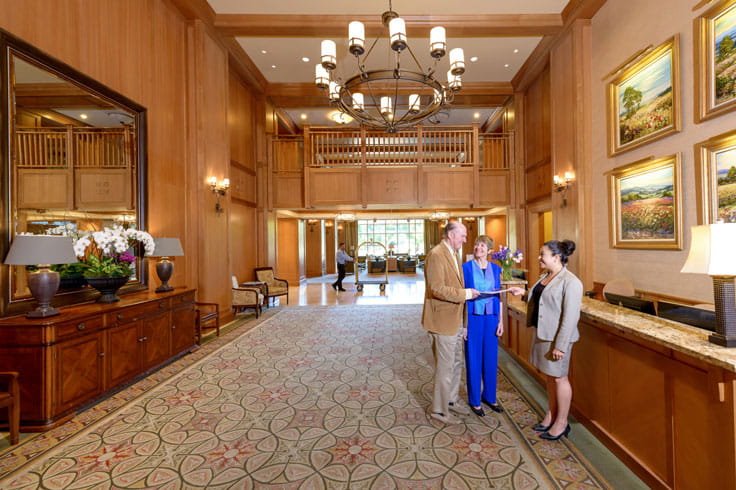 A couple talks to an employee at the front desk.