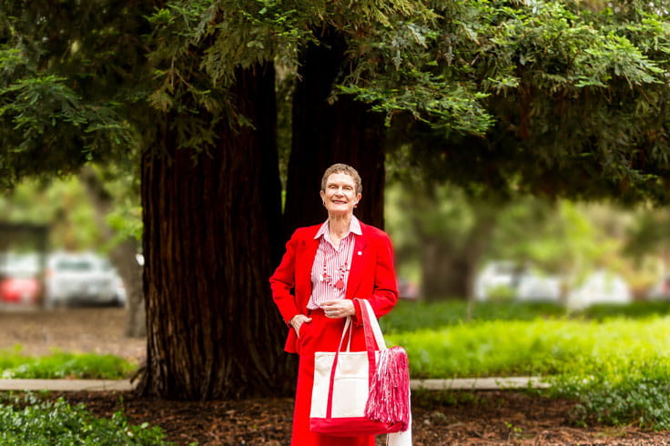 A woman stands outside wearing red.