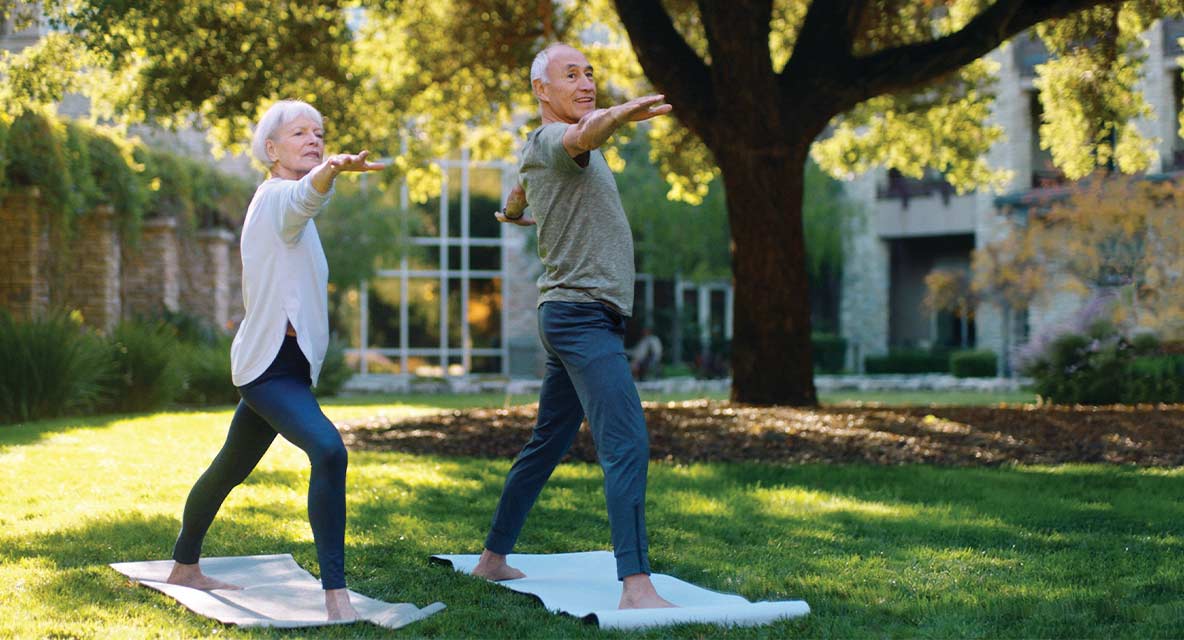 A couple doing yoga outside. 