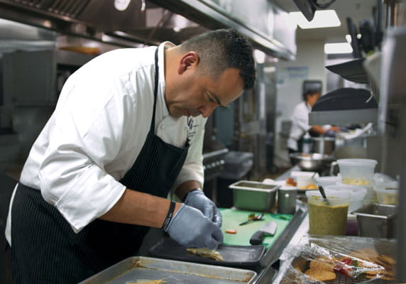 Chef Azmitia prepares dishes in the kitchen.