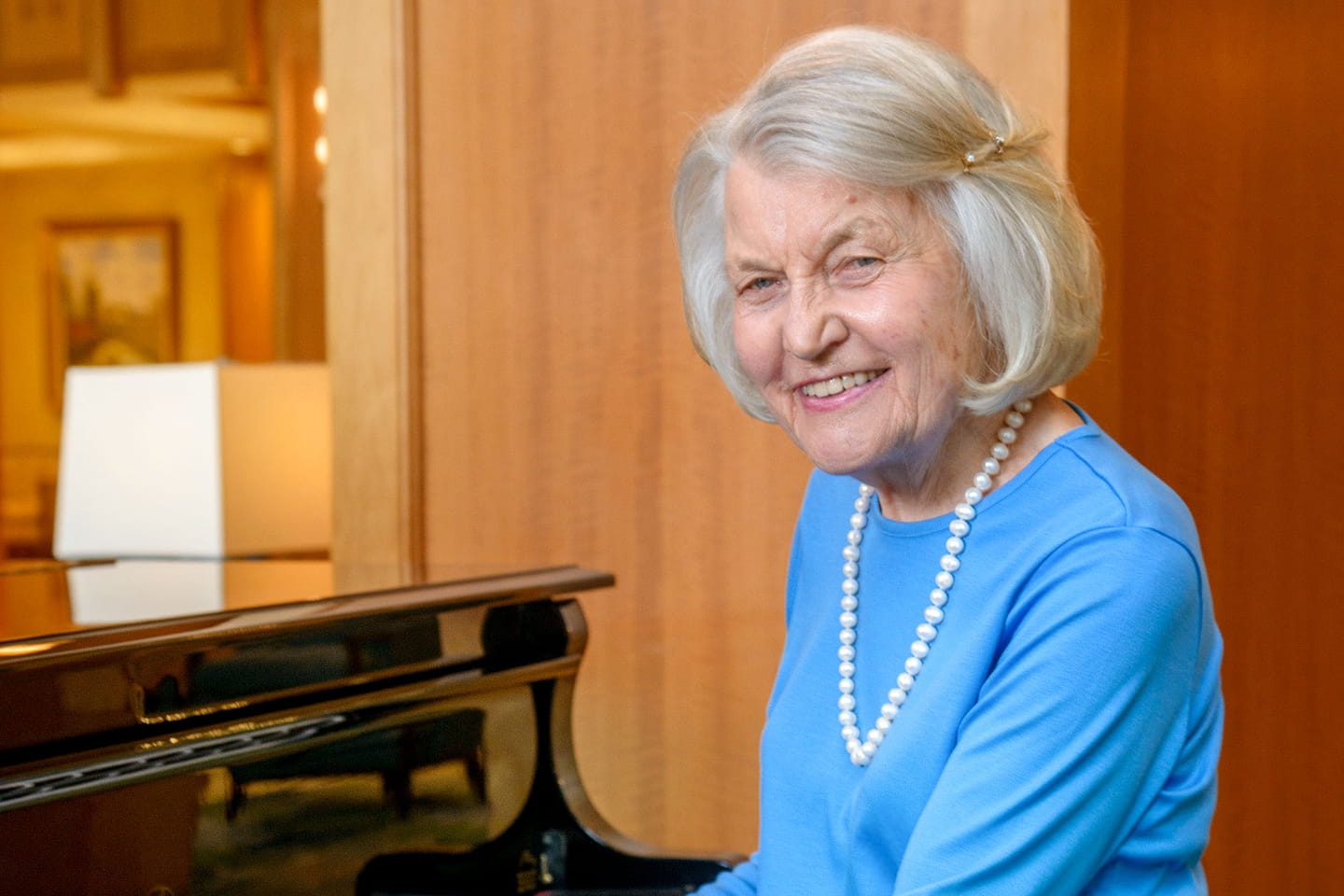 Woman in Vi at Palo Alto living room playing piano. 