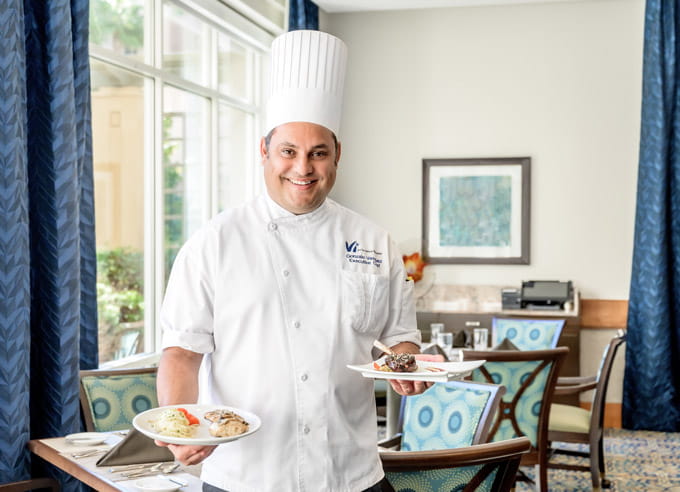 The executive chef holds two plates in the dining room.
