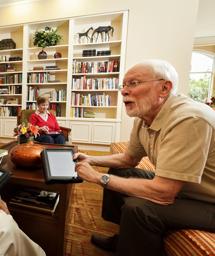 A man discussing something over his e-reader in the Vi at La Jolla Village library