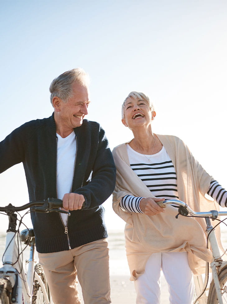 A couple walking with bikes.