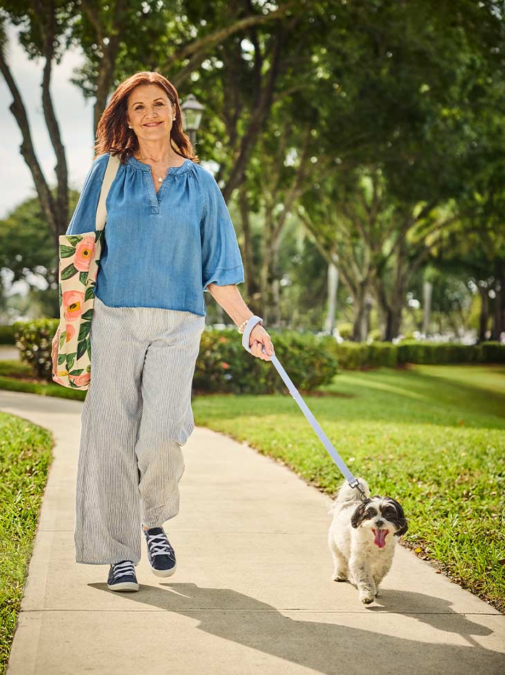 Women walking her dog outside. 