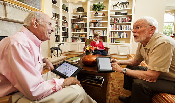 Residents chat while using tablets in the library.