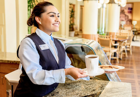 A staff member hands off a cookie and coffee.