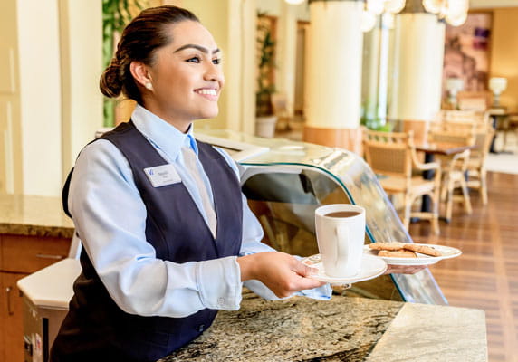 A staff member hands off a cookie and coffee.