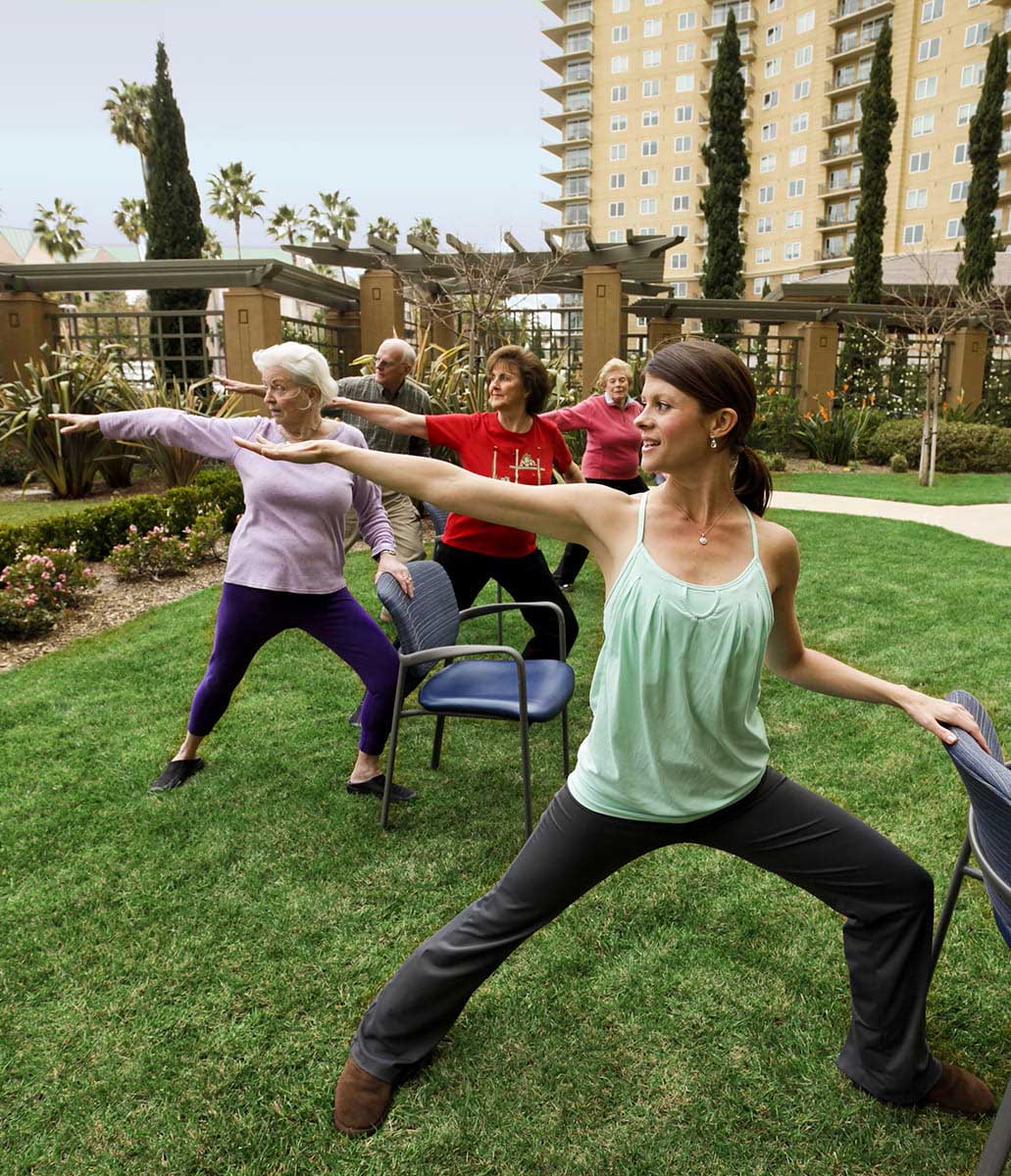 Residents do chair yoga while outside.