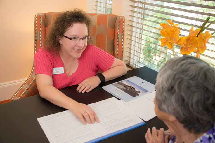 An employee goes through paperwork with a woman.