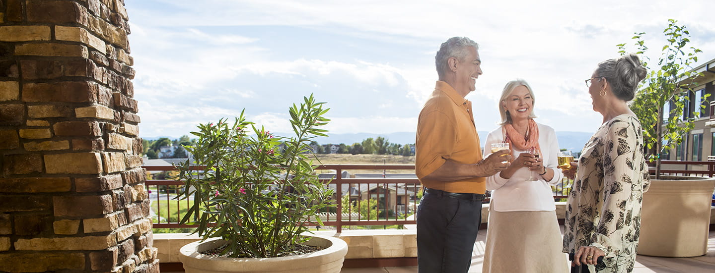 Residents smile and talk in a Vi at Highlands Ranch outdoor space.