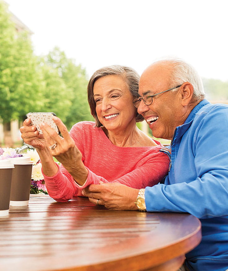 A couple smiles at a smartphone.