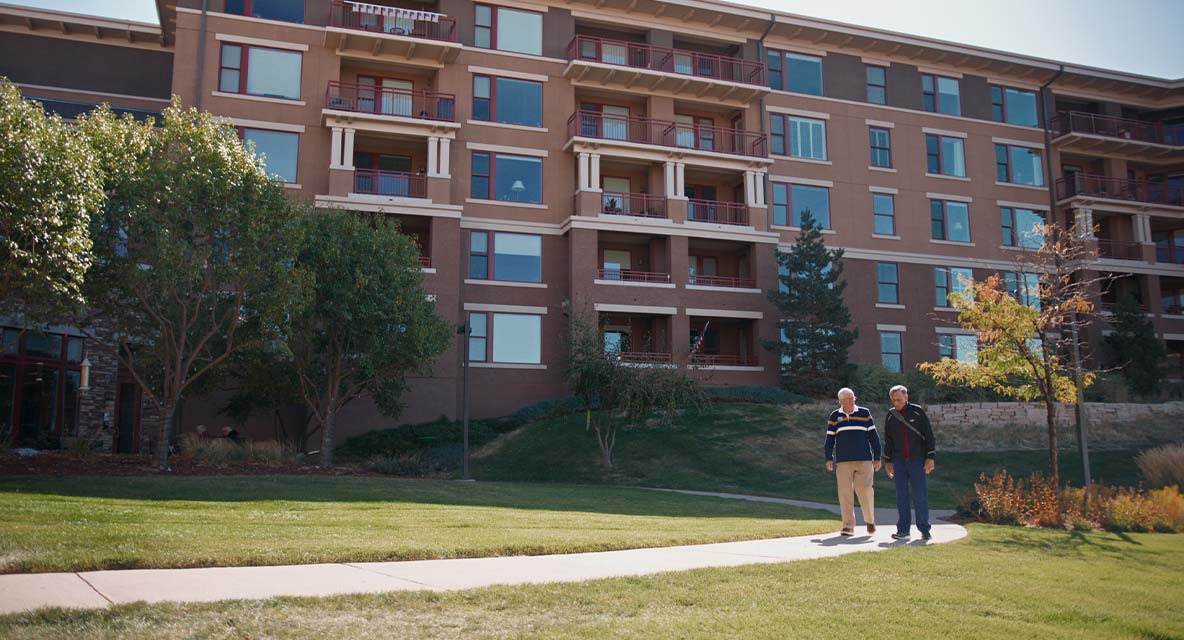 Vi at Highlands Ranch exterior with two men walking.