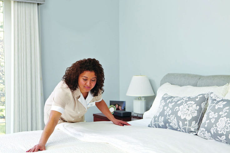 A housekeeper makes a bed.