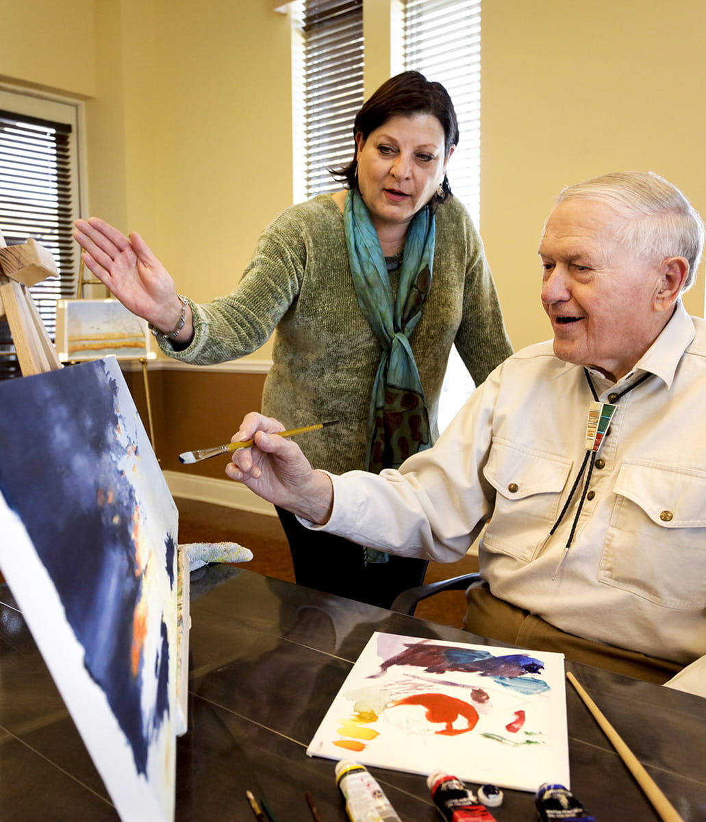 A resident receives art instruction.
