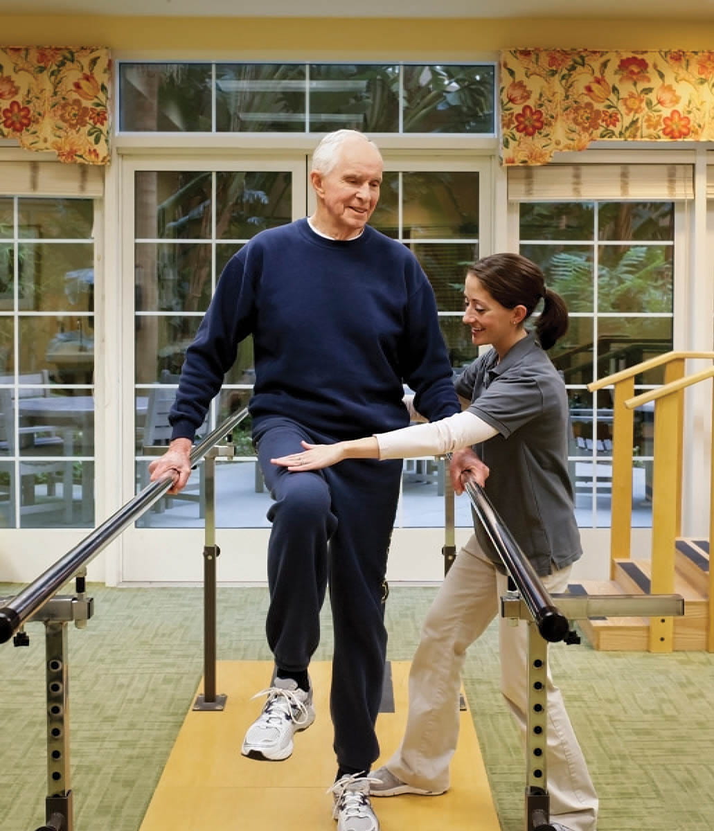 A man does exercises with help from a staff member.