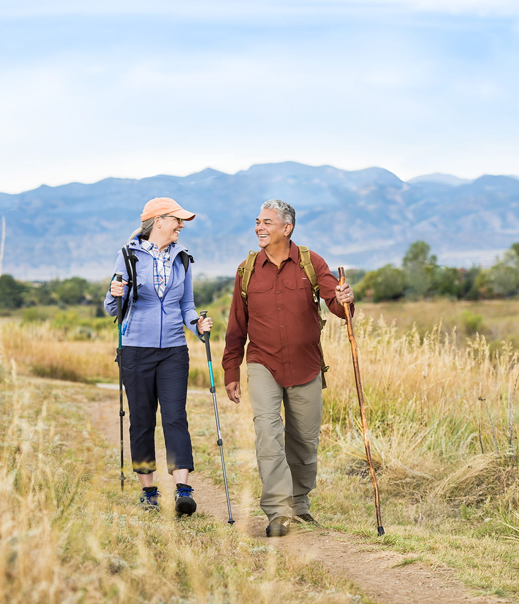 Two people look at each other while hiking near the community.